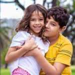 selective focus photography of boy hugging sister