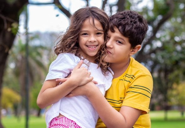 selective focus photography of boy hugging sister