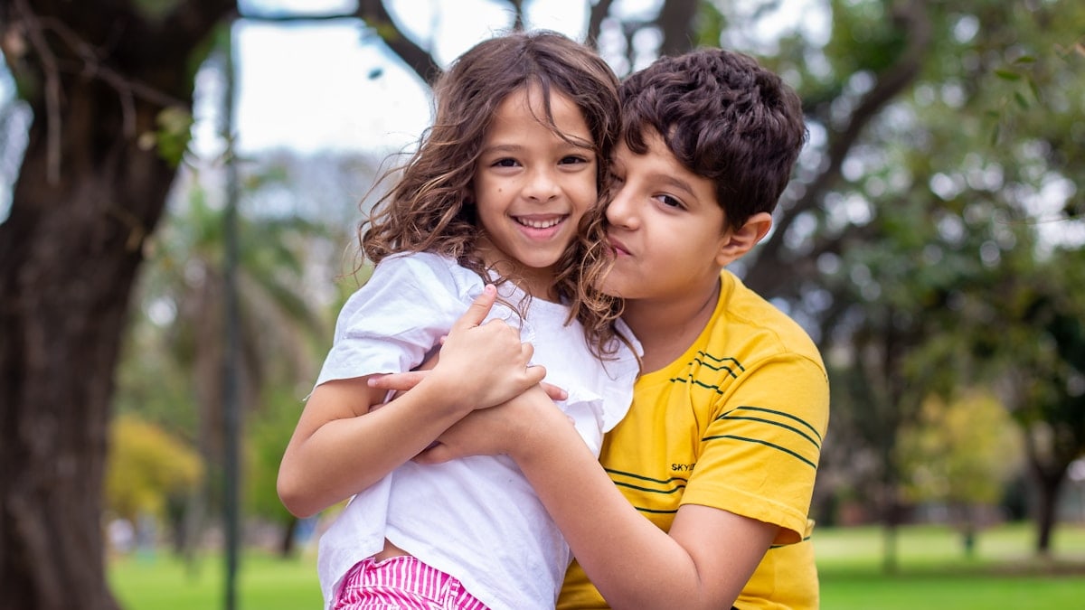 selective focus photography of boy hugging sister