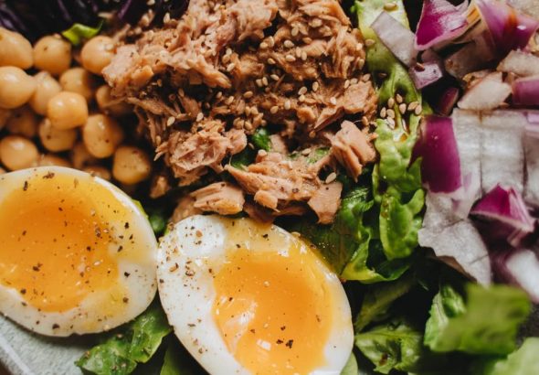 Close-up of a nutritious salad with tuna, soft-boiled eggs, and fresh vegetables.
